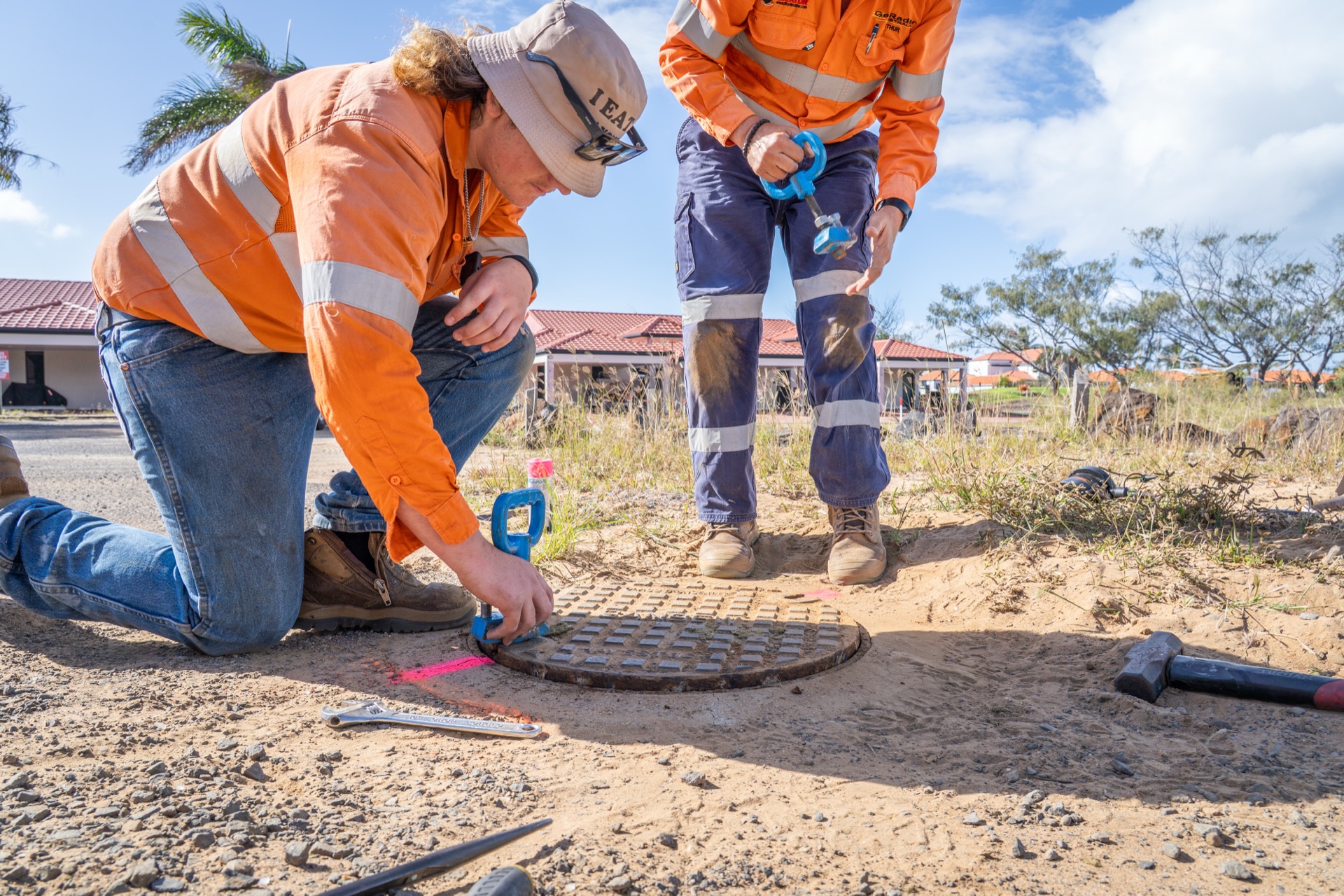 A younger GeoRadar crew member marking a located service while a workmate stands by